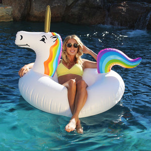 a woman in a yellow bikini top sitting on a unicorn inflatable